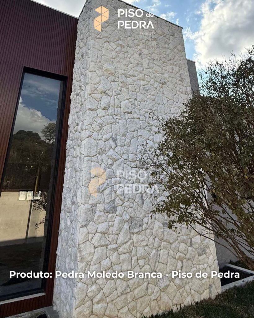Fachada imponente com pedra moledo branca, em harmonia com a porta de madeira.